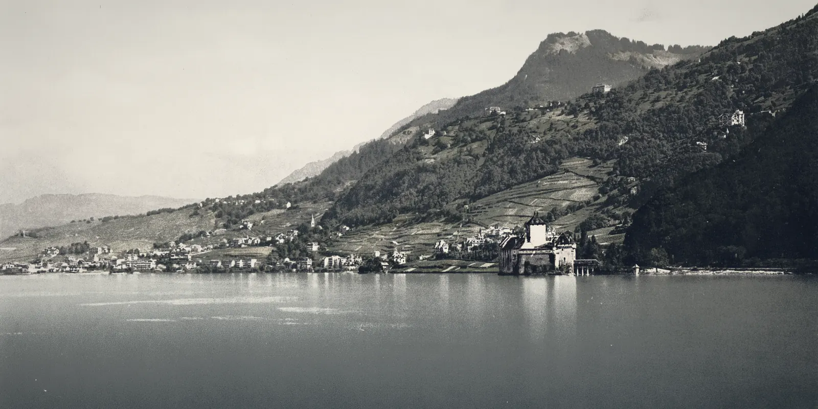 A lakeside castle beneath mountains on Lake Geneva