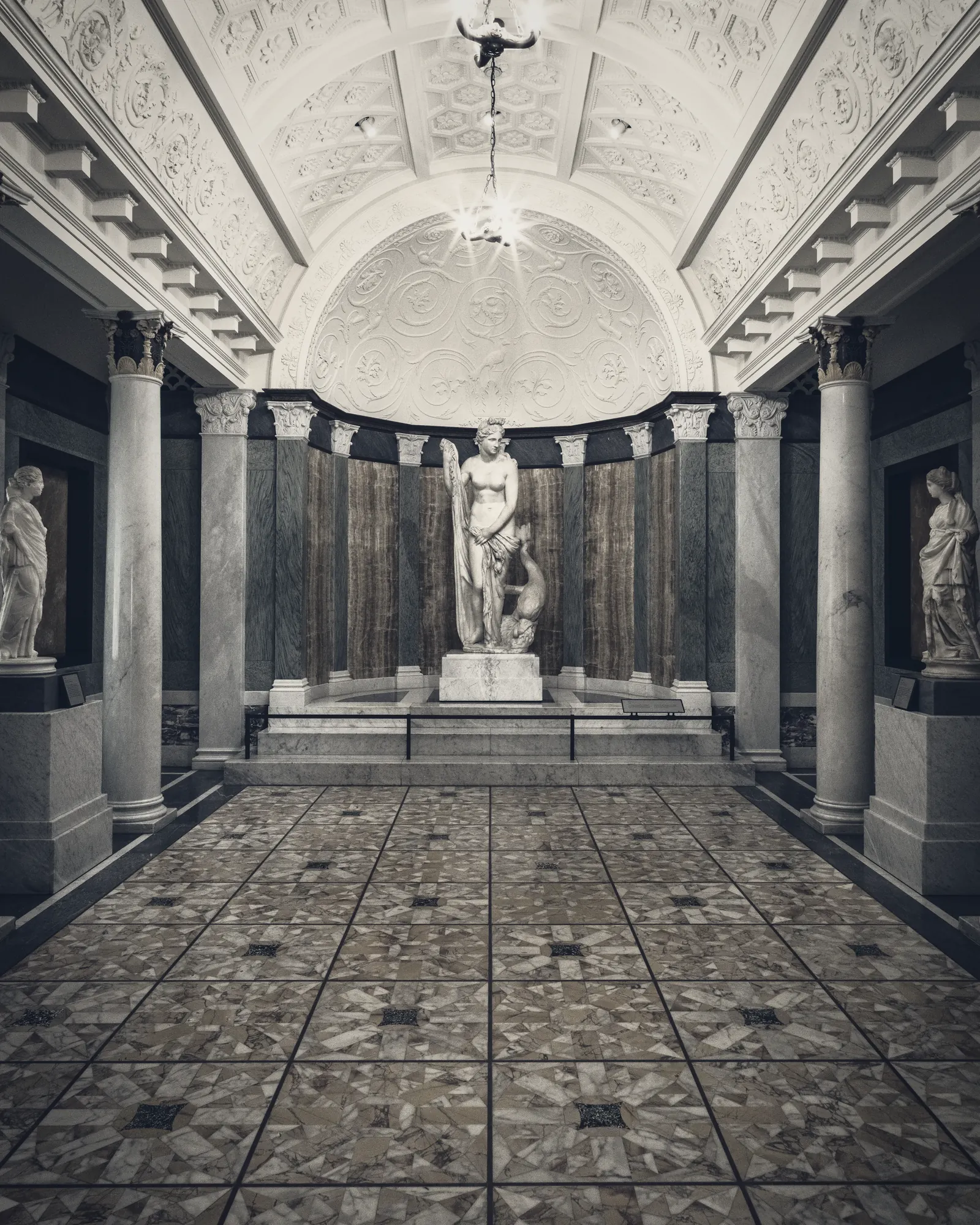 A sculpture gallery with a single figure at its end